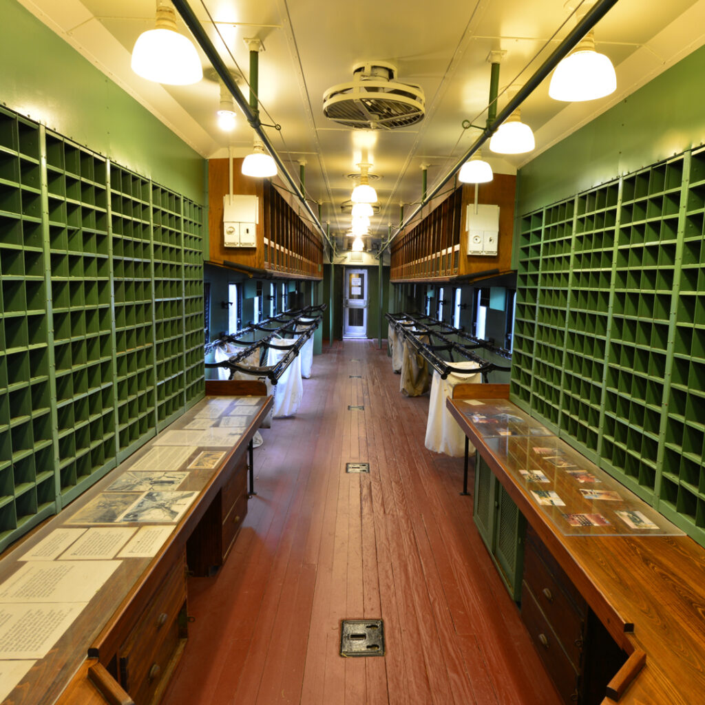 Interior of a vintage railway mail car with sorting cubbies and wooden benches